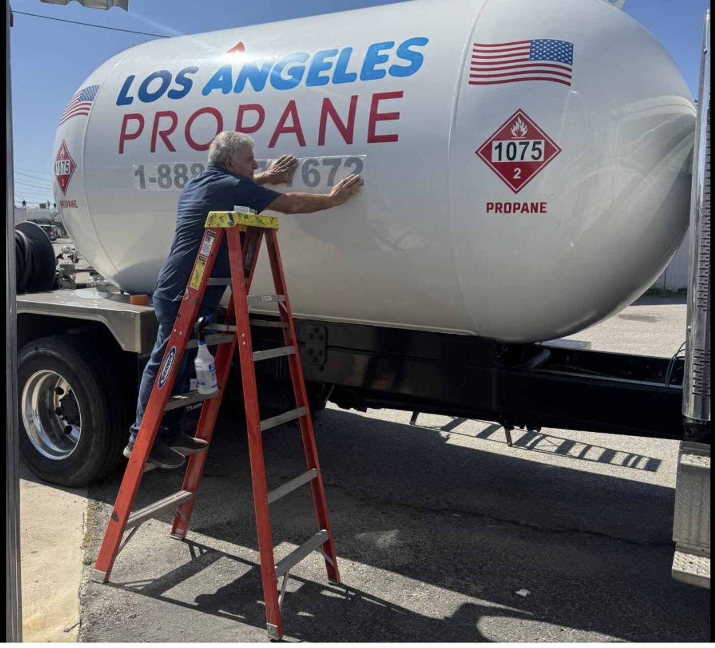 A Los Angeles Propane crew member applying the company logo to a real delivery tanker truck